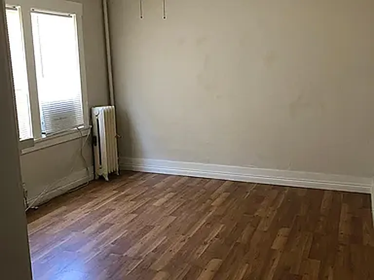 Studio main room with a tall window, vintage radiator and wood floors